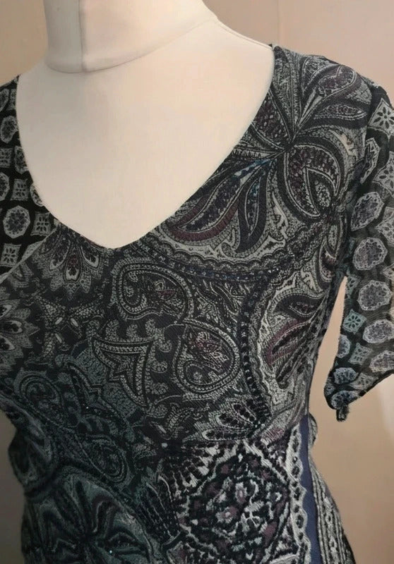 A short-sleeve V-neck dress 
with an intricate paisley pattern in black, gray, and white, displayed on a white mannequin torso.