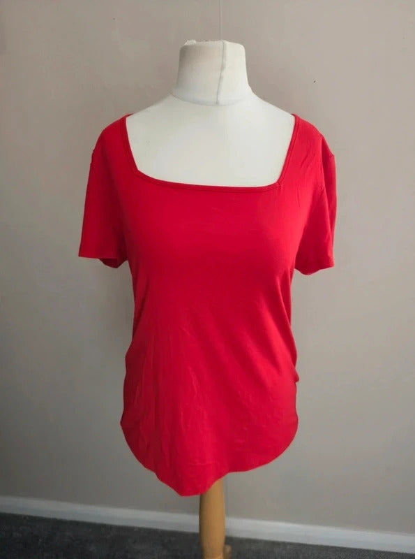 A bright red short-sleeve top with a square neckline, displayed on a white dress form mannequin against a plain beige wall.