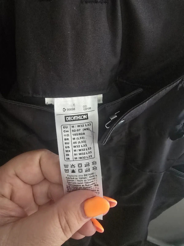 A close-up of a hand holding a white Decathlon garment care label sewn onto a black jacket or hoodie.