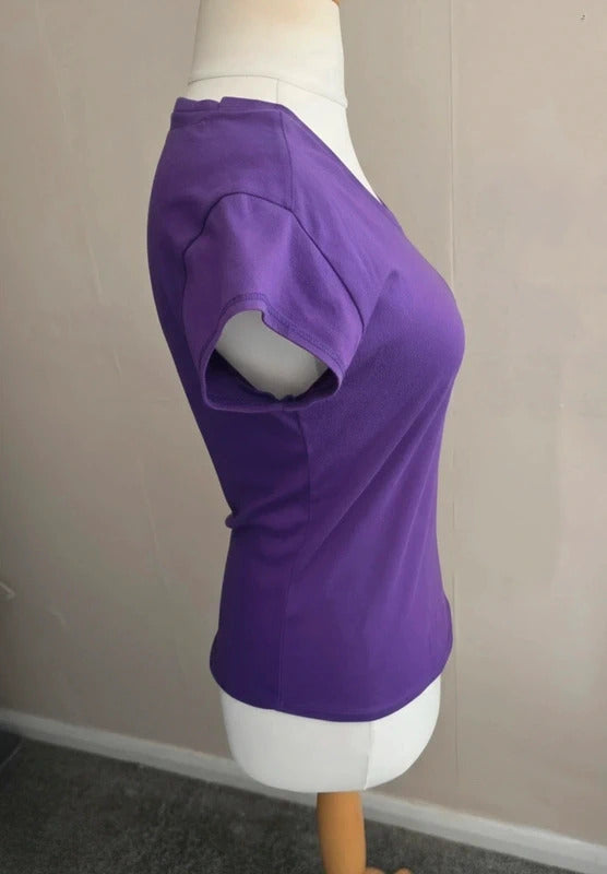 A purple short-sleeve scoop neck top displayed on a white mannequin torso, photographed indoors against a plain beige wall.