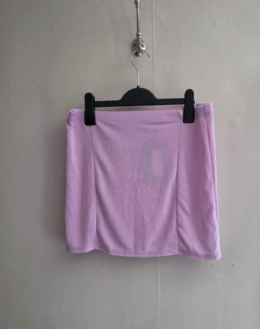 A light purple athletic mini skirt hanging from a black plastic hanger against a plain gray wall.